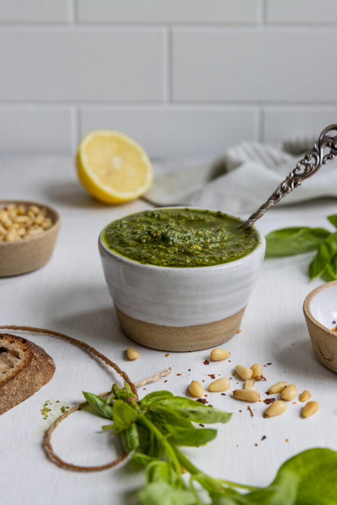 Dairy free basil pesto in a white bowl with a spoon