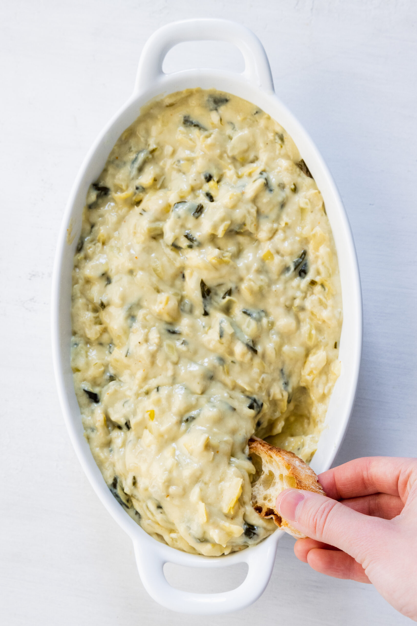 Bacon spinach artichoke dip served in a white baking dish