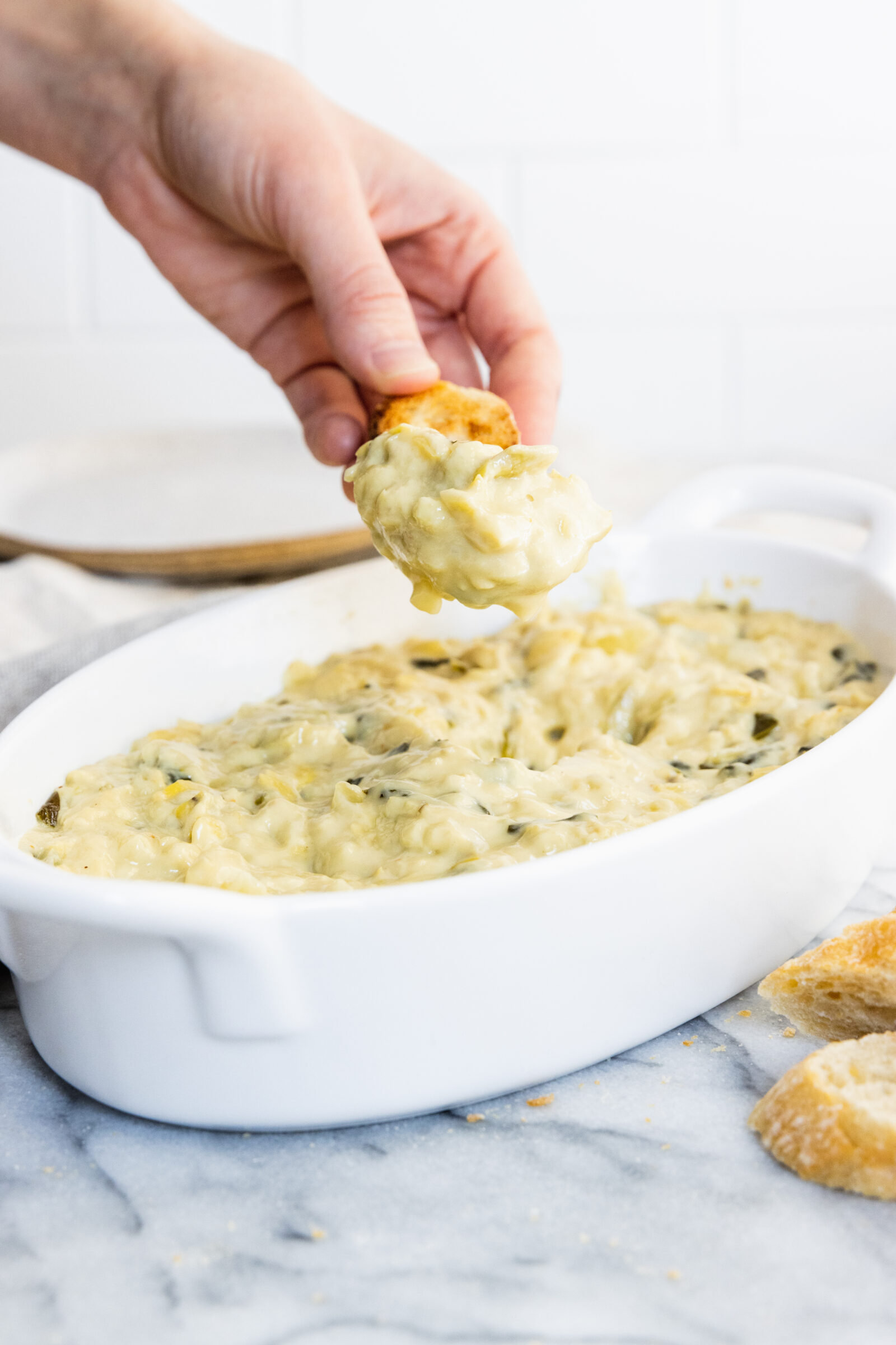 Vegan artichoke dip served in a white baking dish