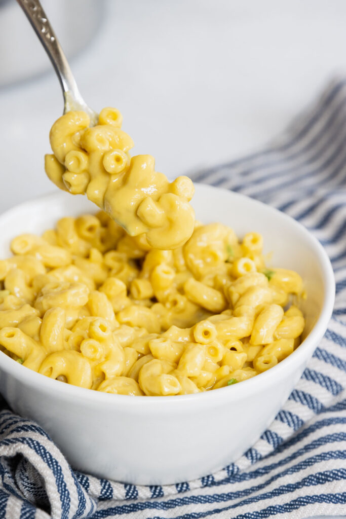 Vegan mac and cheese served in a white bowl with a fork