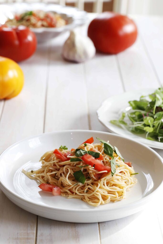 Angel Hair Pasta with fresh tomatoes and basil served on a white plate