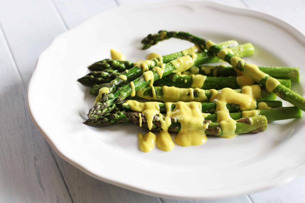 Asparagus with Vegan Hollandaise served on a white plate