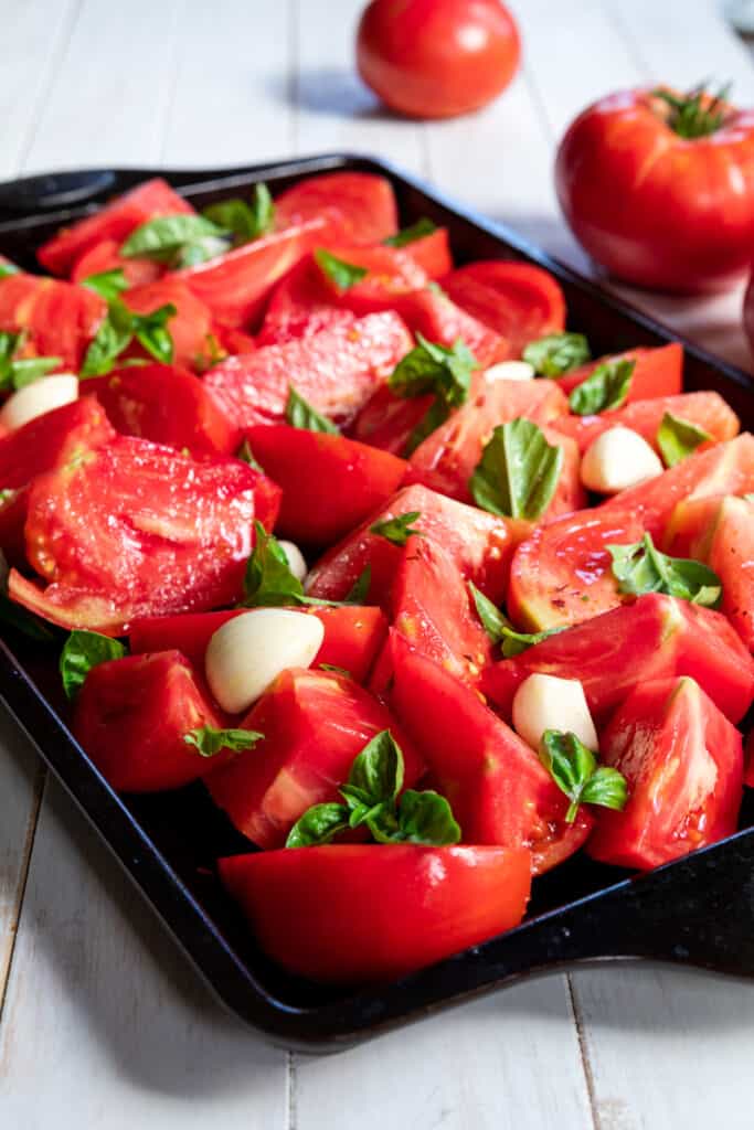 Tomatoes, garlic, and basil on a baking sheet tray