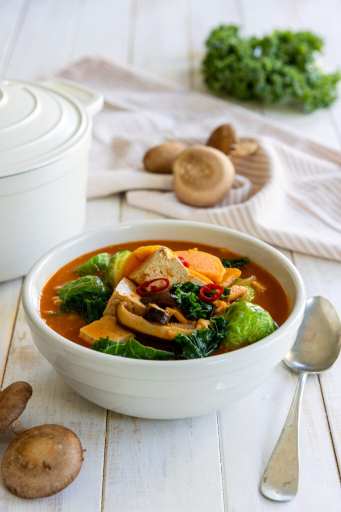 Fall Sweet Potato Kale Coconut Curry Soup in a white bowl with a spoon