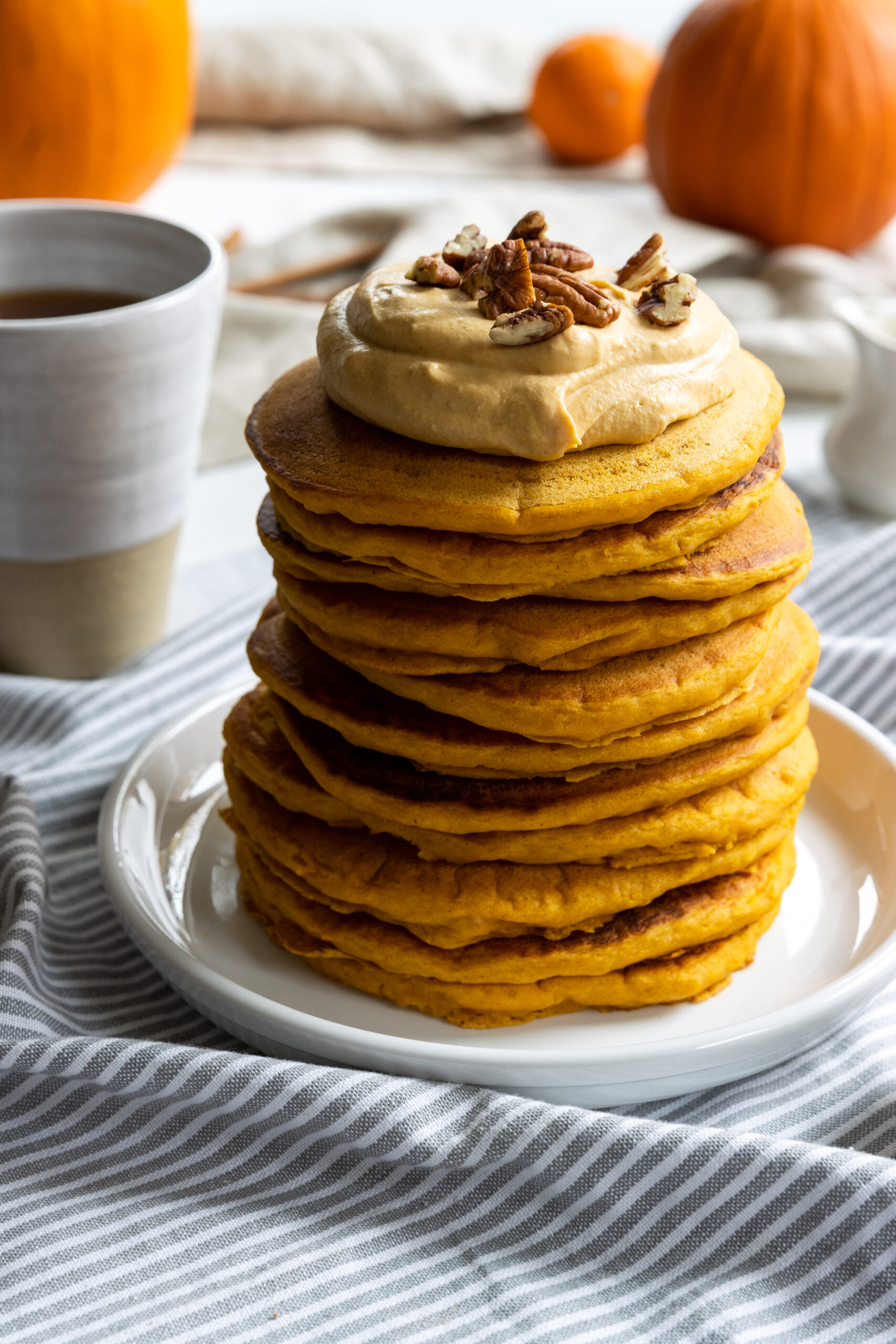 Pumpkin Pancakes stacked on a white plate with Vegan Pumpkin Cream