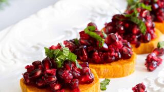 Roasted Sweet Potato Slices with Fresh Cranberry and Pomegranate Relish Served on a White Plate