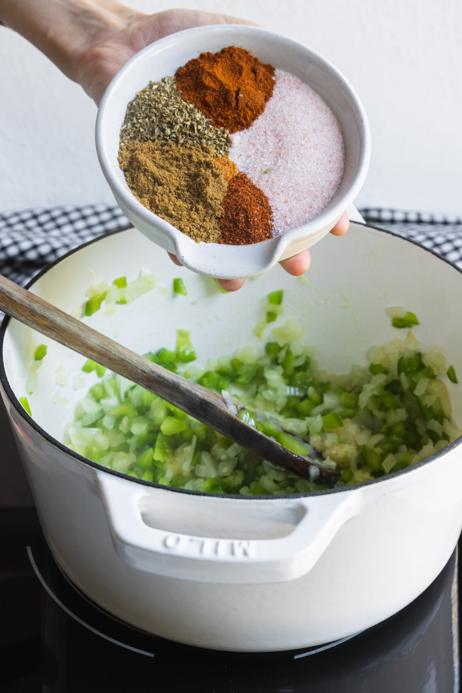 Adding seasoning to the pot for plant based chili