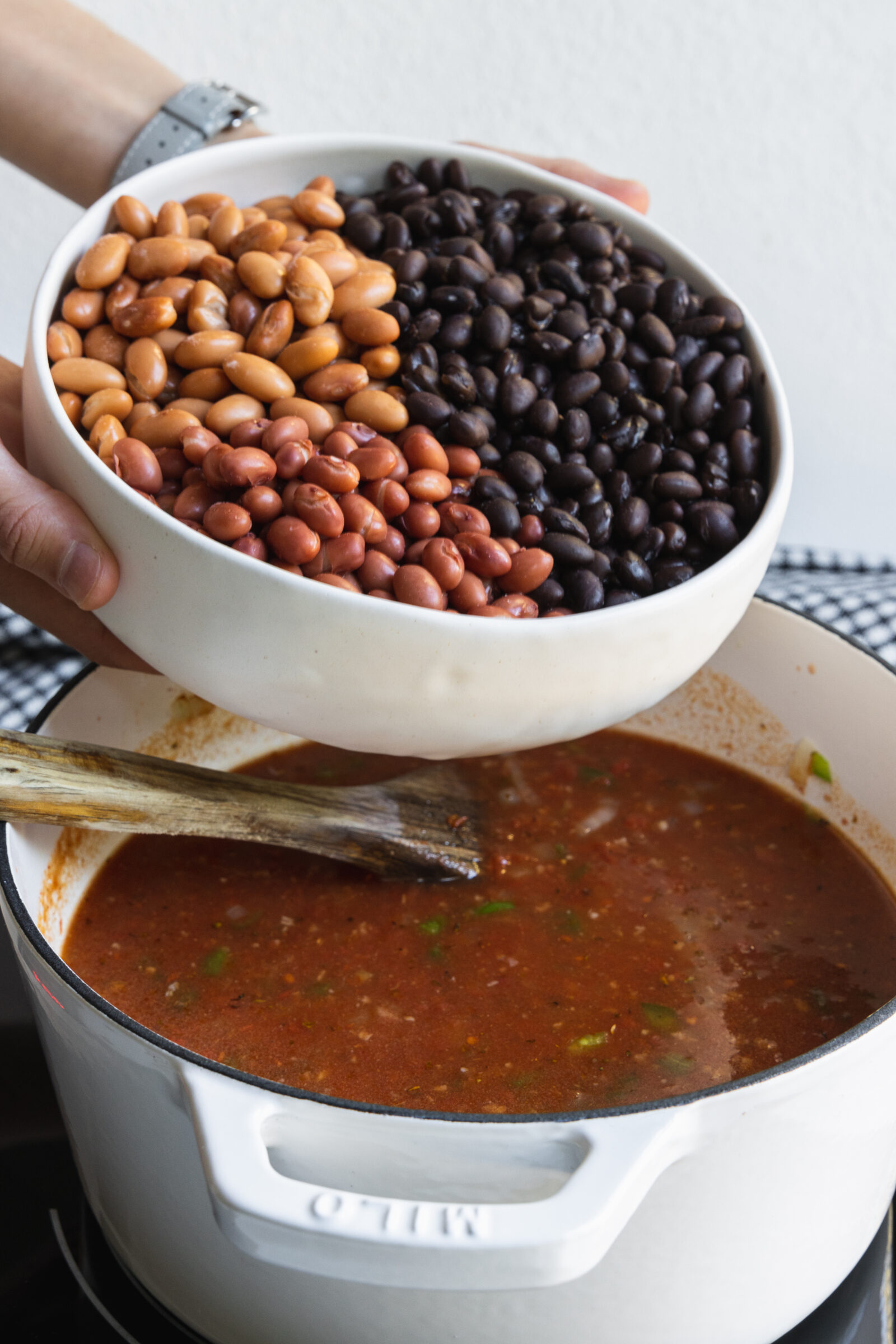 Adding beans to the pot for plant-based chili