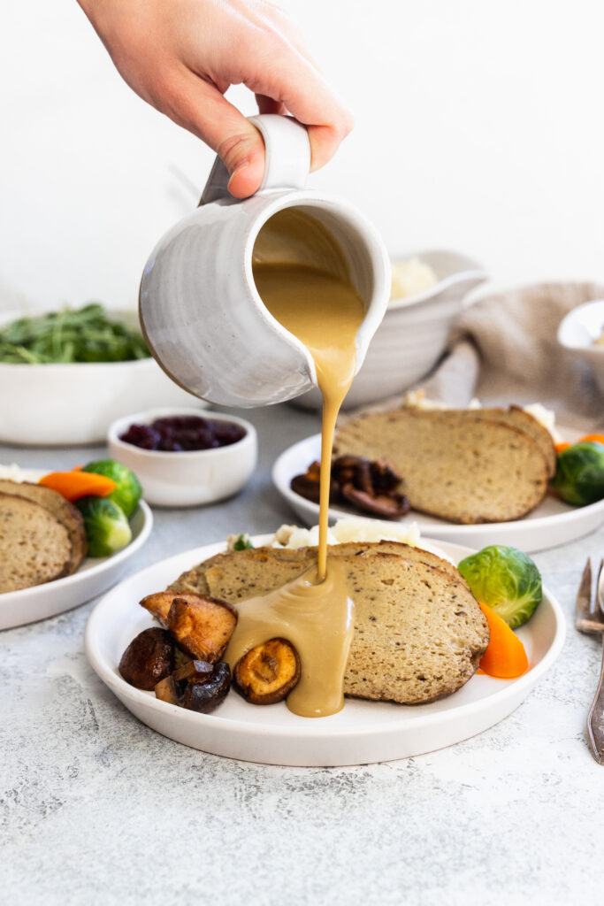 Pouring vegan gravy over vegan turkey roast