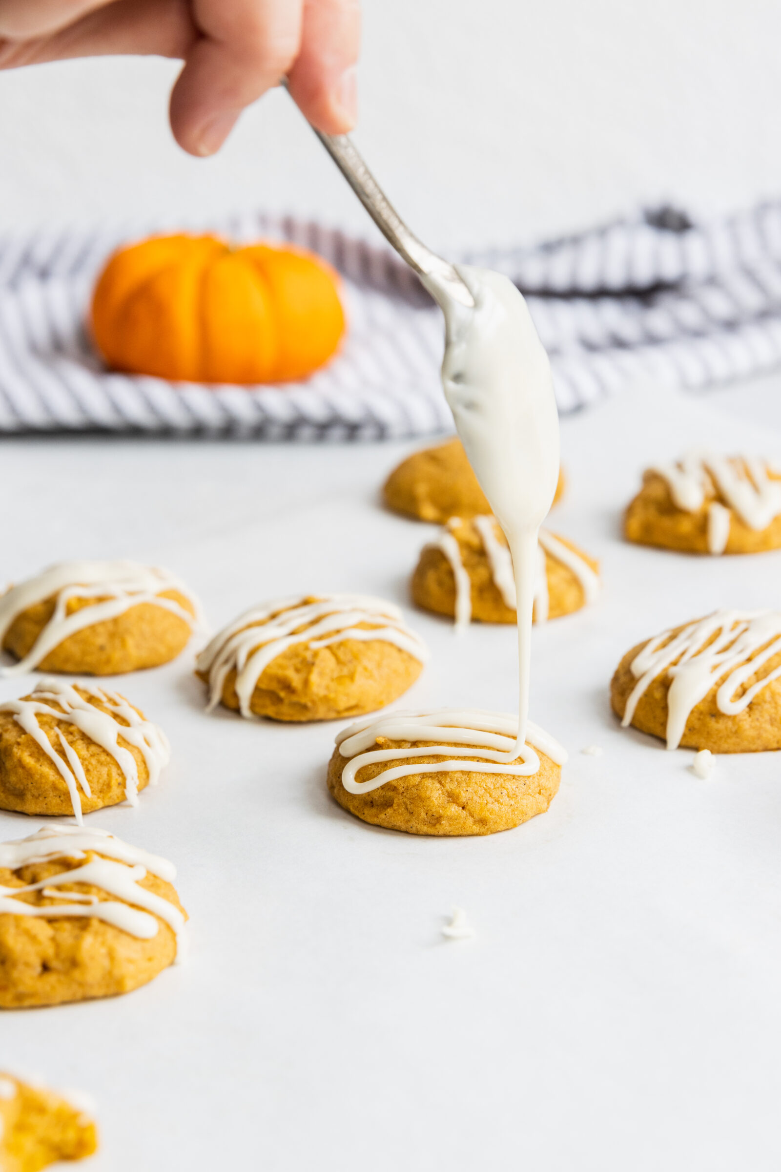 Drizzling maple glaze over the pumpkin cookies