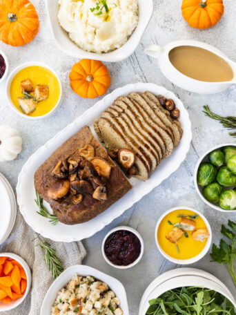 Vegan turkey roast served on a platter in the middle of a Holiday table