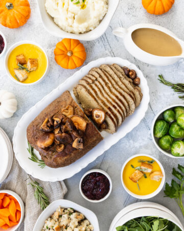 Vegan turkey roast served on a platter in the middle of a Holiday table