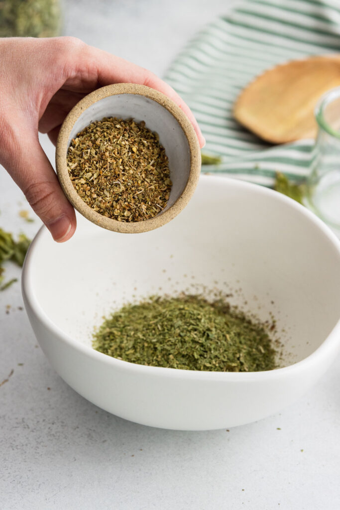 Adding dried marjoram to a bowl