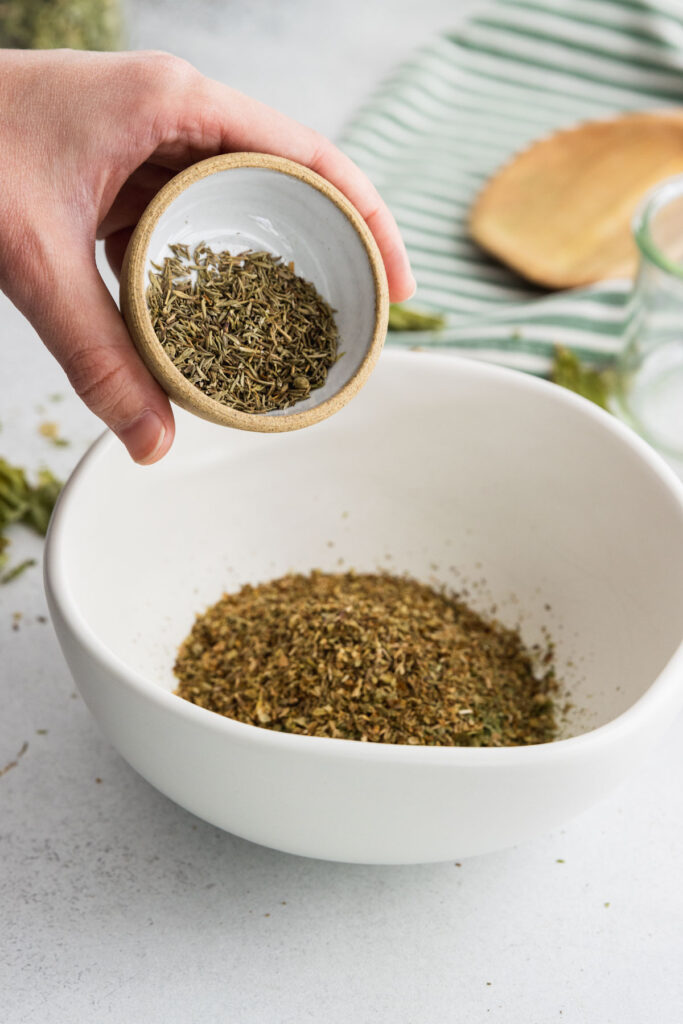 Adding dried rosemary to a bowl