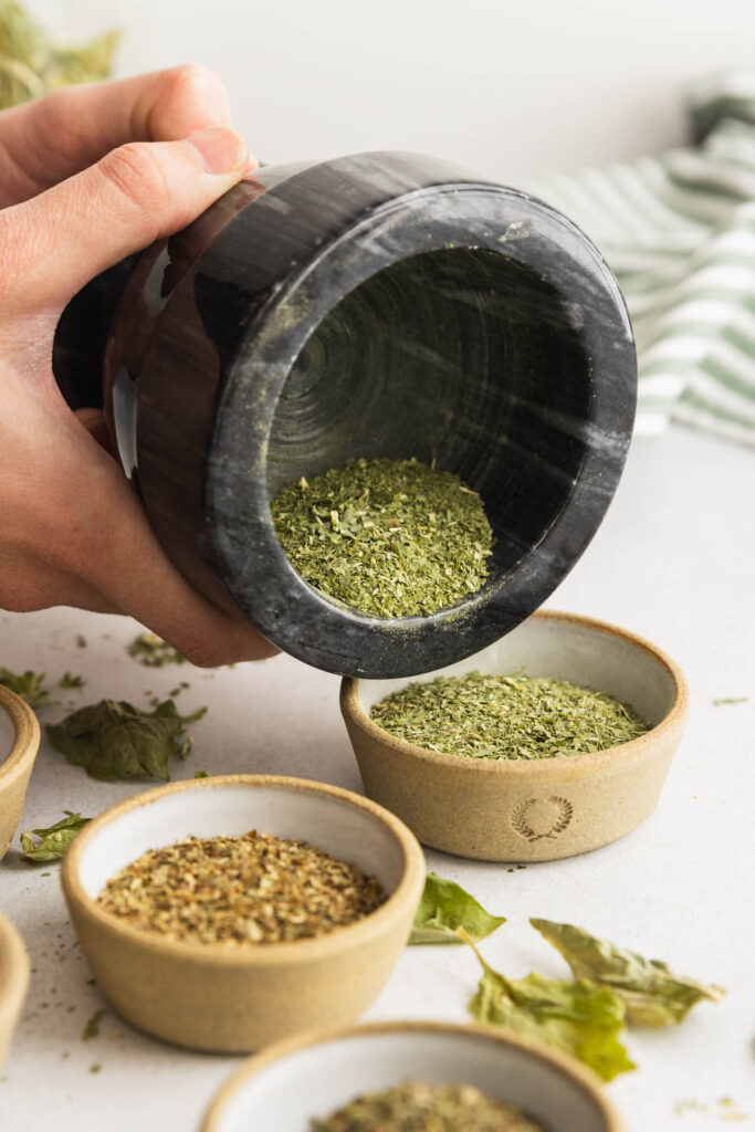 Pouring the ground basil leaves into a small bowl