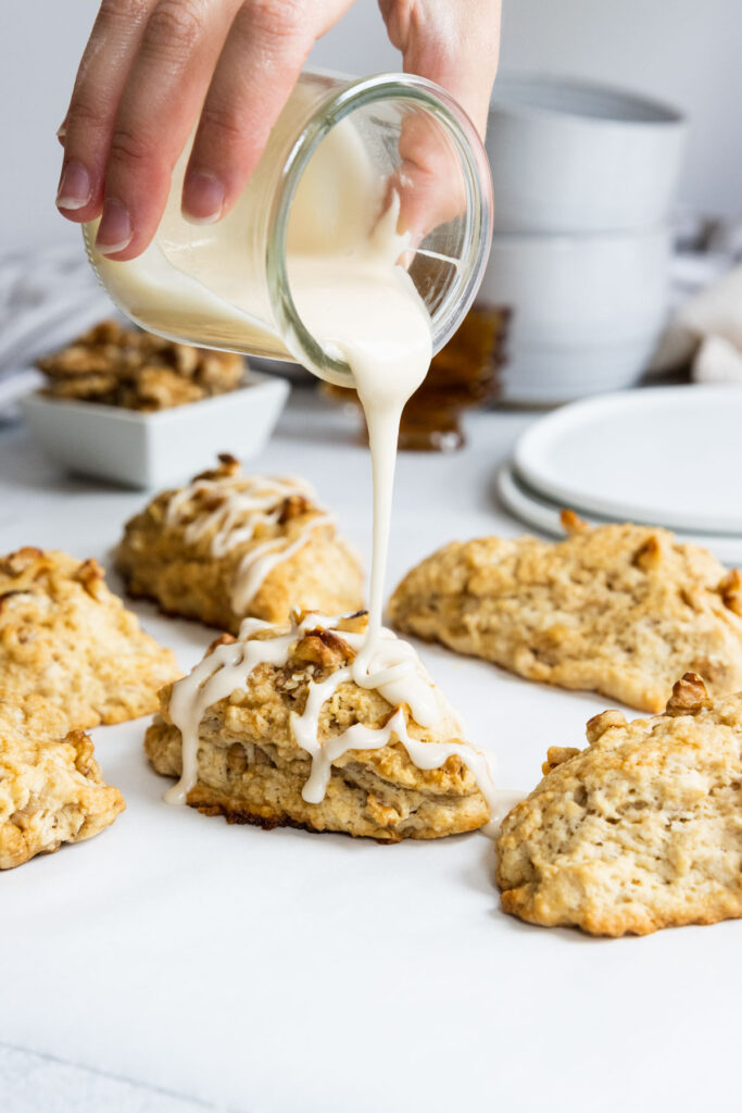 Pouring maple glaze on maple scones with walnuts