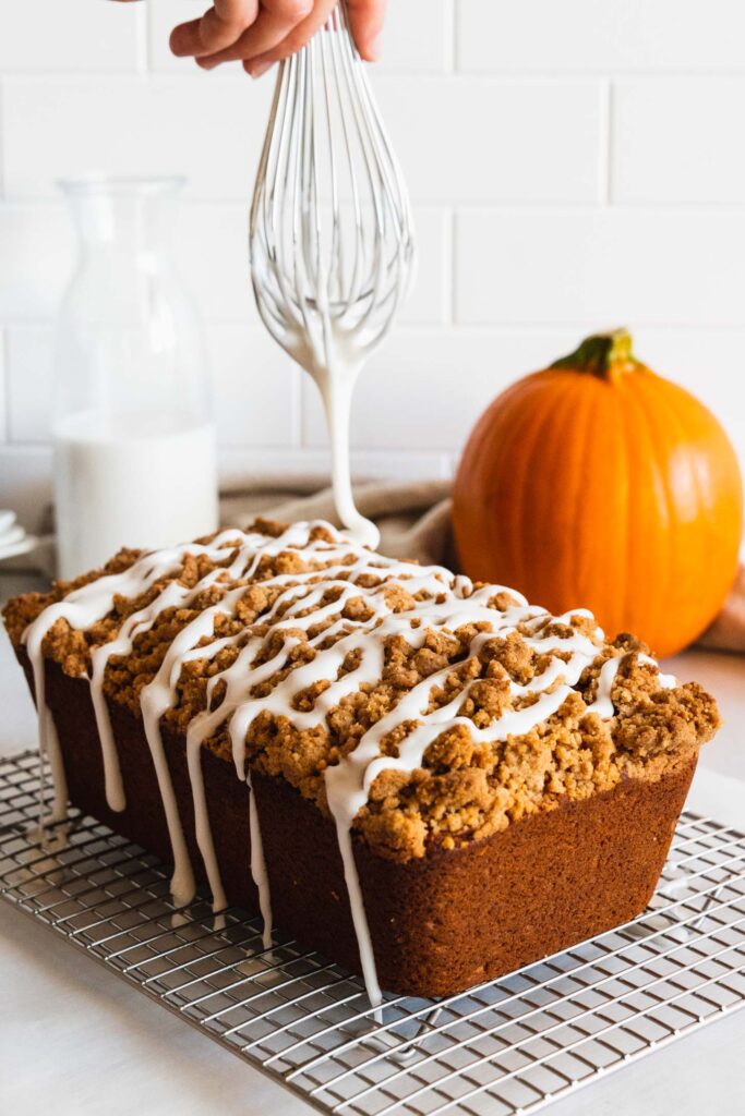 Drizzling a glaze over the vegan pumpkin bread