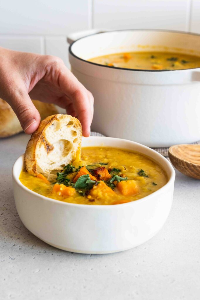Dunking a slice of crusty bread in the red lentil sweet potato soup