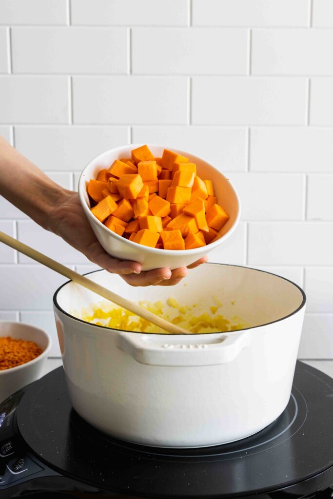 Adding chopped sweet potato to the red lentil sweet potato soup