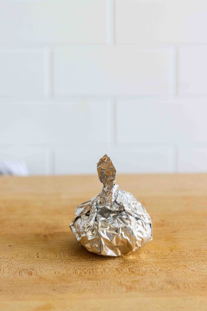 A garlic bulb wrapped in foil before roasting