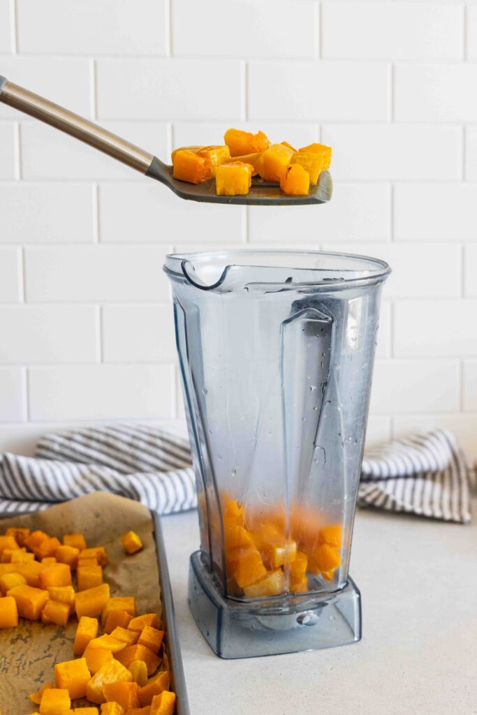Adding the roasted butternut squash to a blender