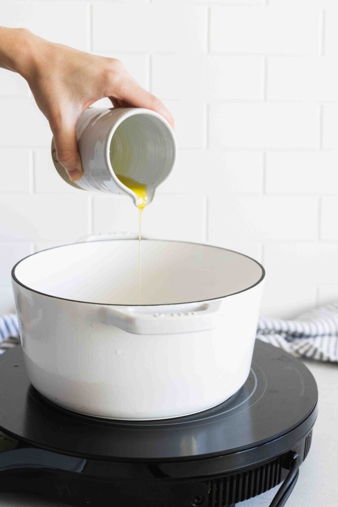 Adding olive oil to a pot
