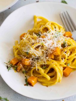 Vegan roasted butternut squash pasta served with slices of bread and sage garnish