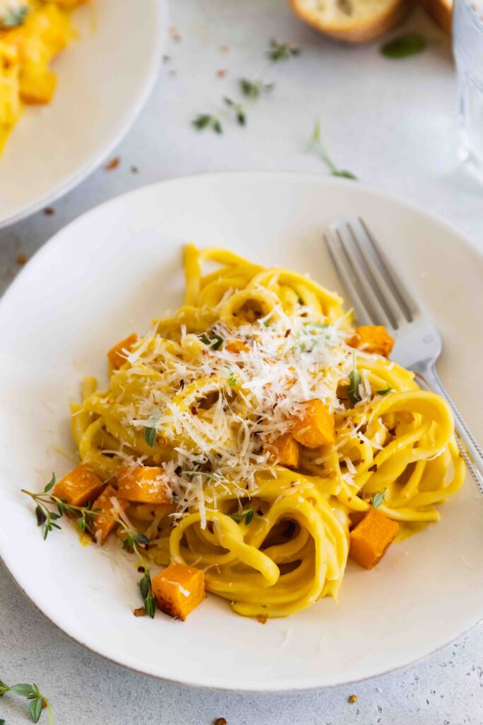 Roasted butternut squash pasta plated on a white plate with a fork