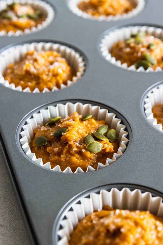 Vegan pumpkin muffins topped with pumpkin seeds before baking