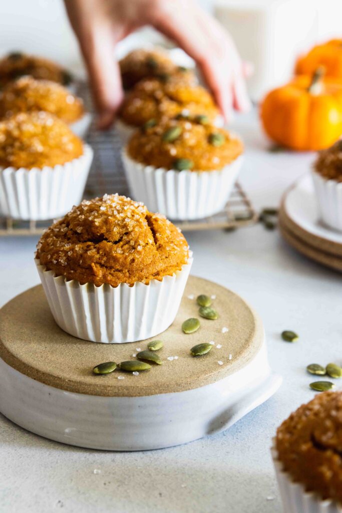 Vegan Pumpkin Muffin served on a plate with more muffins on a cooling rack in the background