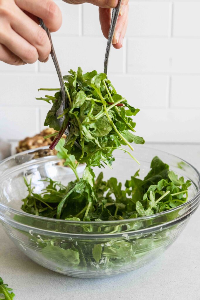 Tossing the salad greens with the dressing