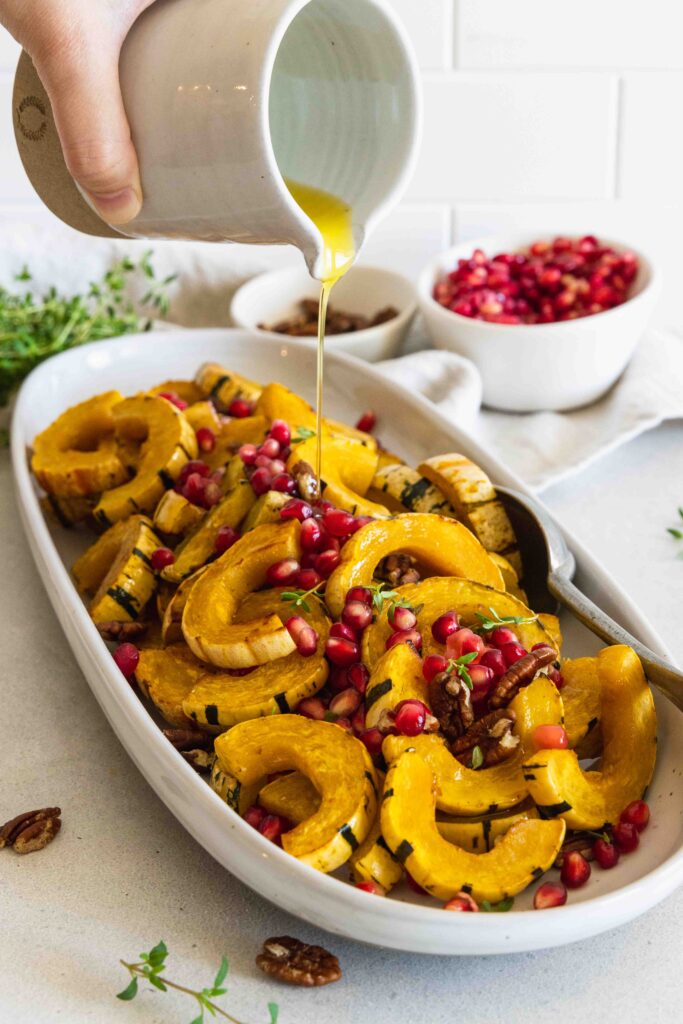 Drizzling olive oil over the roasted delicata squash