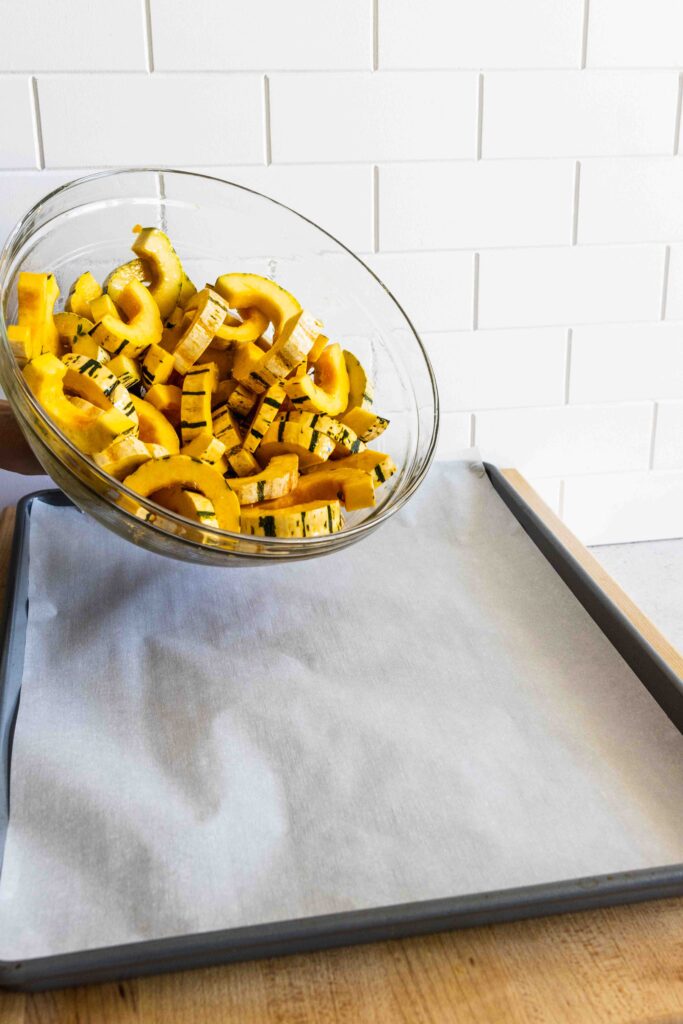 Pouring the delicata squash out on a baking sheet