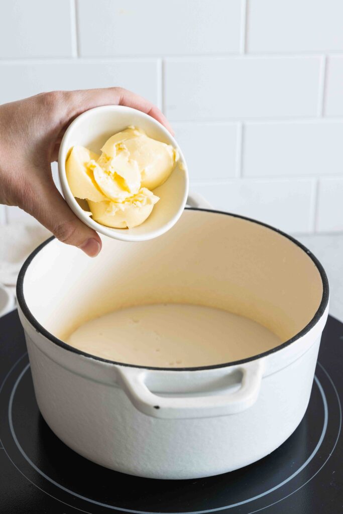 Adding margarine to the warming milk in the pot