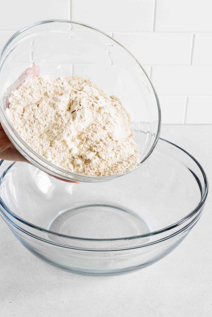 Adding all purpose flour and whole wheat flour to a bowl