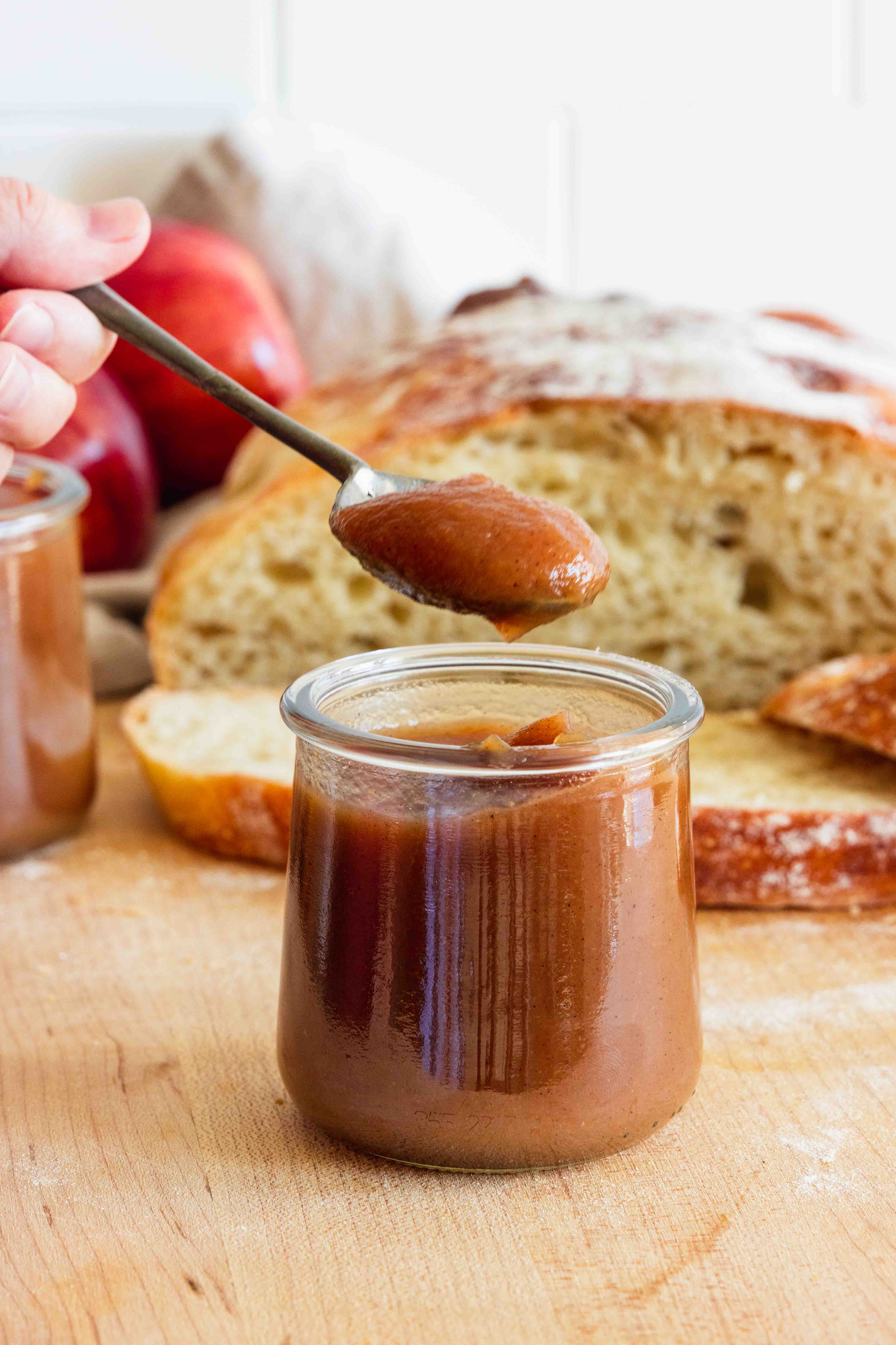 Apple Butter in a jar and a spoon full of apple butter.