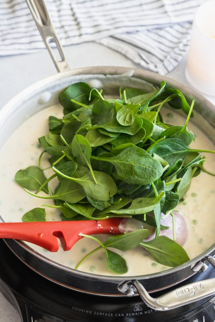 Fresh Spinach adding to the vegan cream sauce