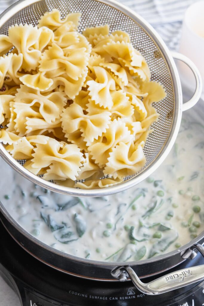 Adding the cooked pasta to the creamy vegan pasta sauce