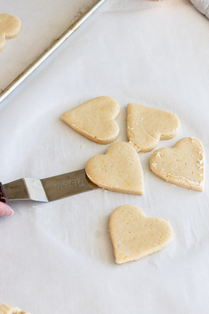 Using an offset spatular to move the cookies to a baking sheet tray