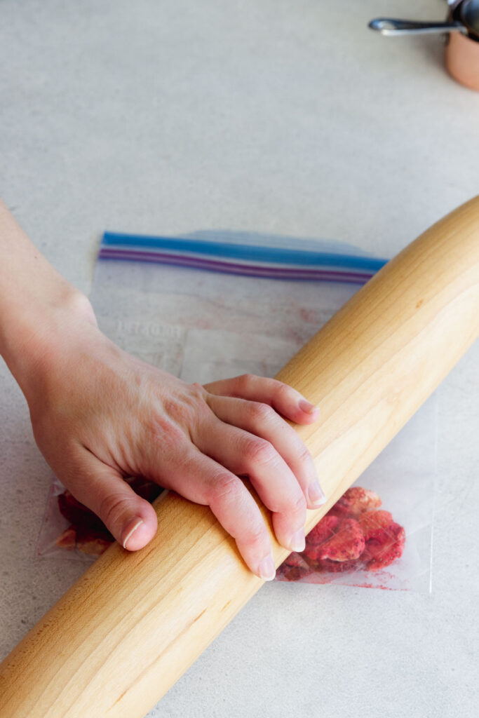 Crushing freeze dried strawberries in a ziplock bag with a rolling pin