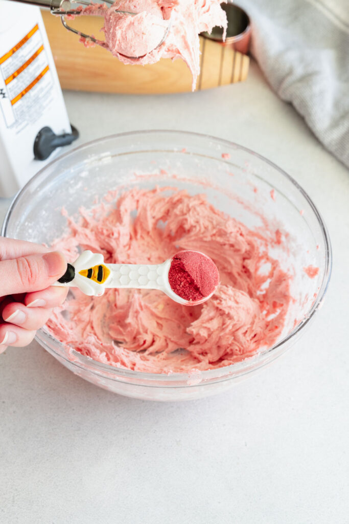 Adding the strawberry powder to the whipped forsting mixture to add color and flavor