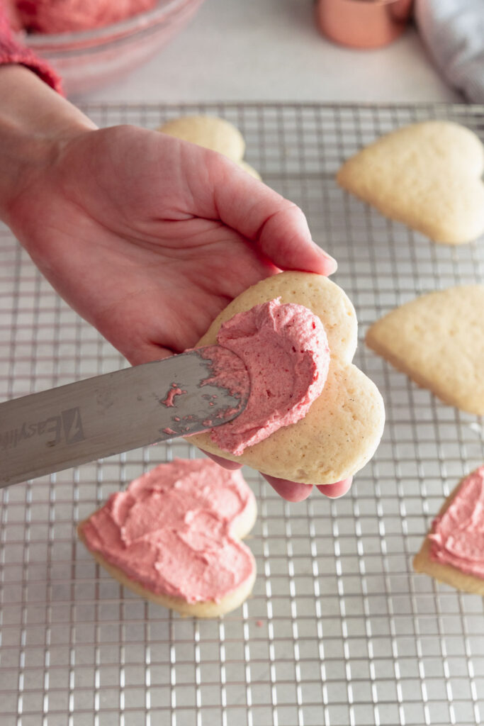 Spreading the frosting on the soft sugar cookies