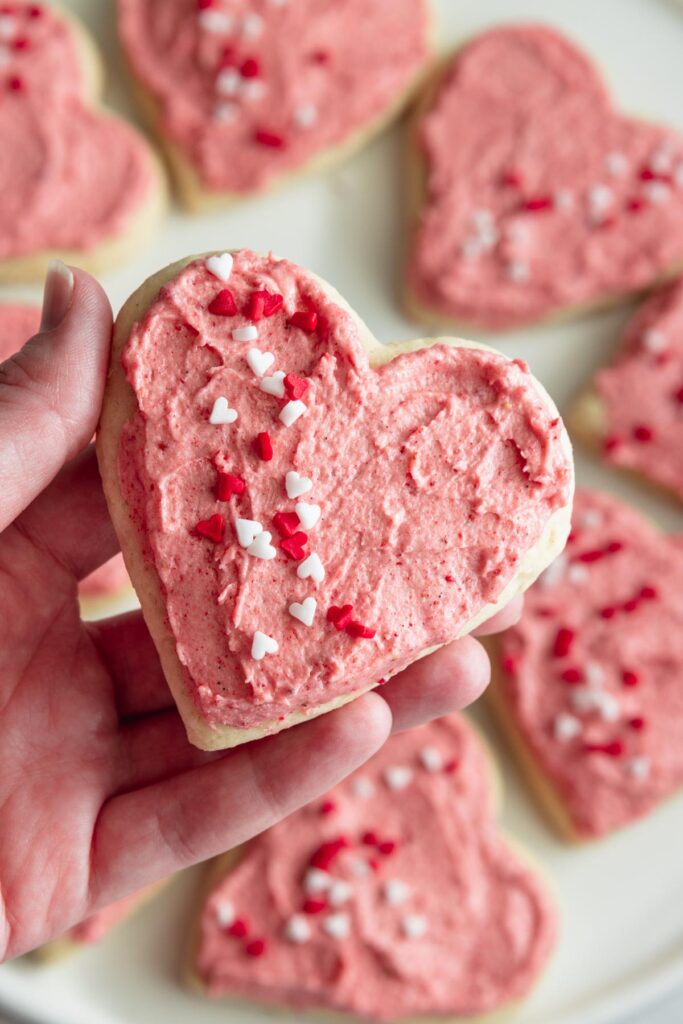 Vegan Lofthouse-style sugar cookie topped with fluffy pink frosting and heart sprinkles