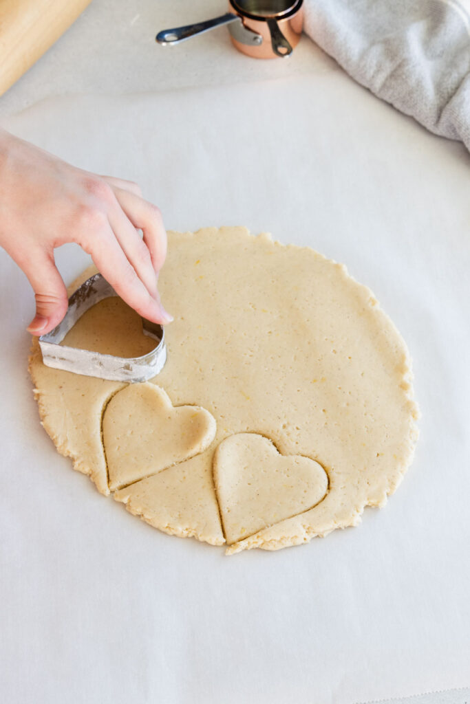 Using cookie cutters to cut the cookies out of the dough