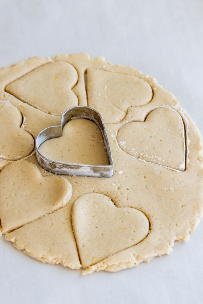 Cutting out the cookies with a heart shaped cookie cutter