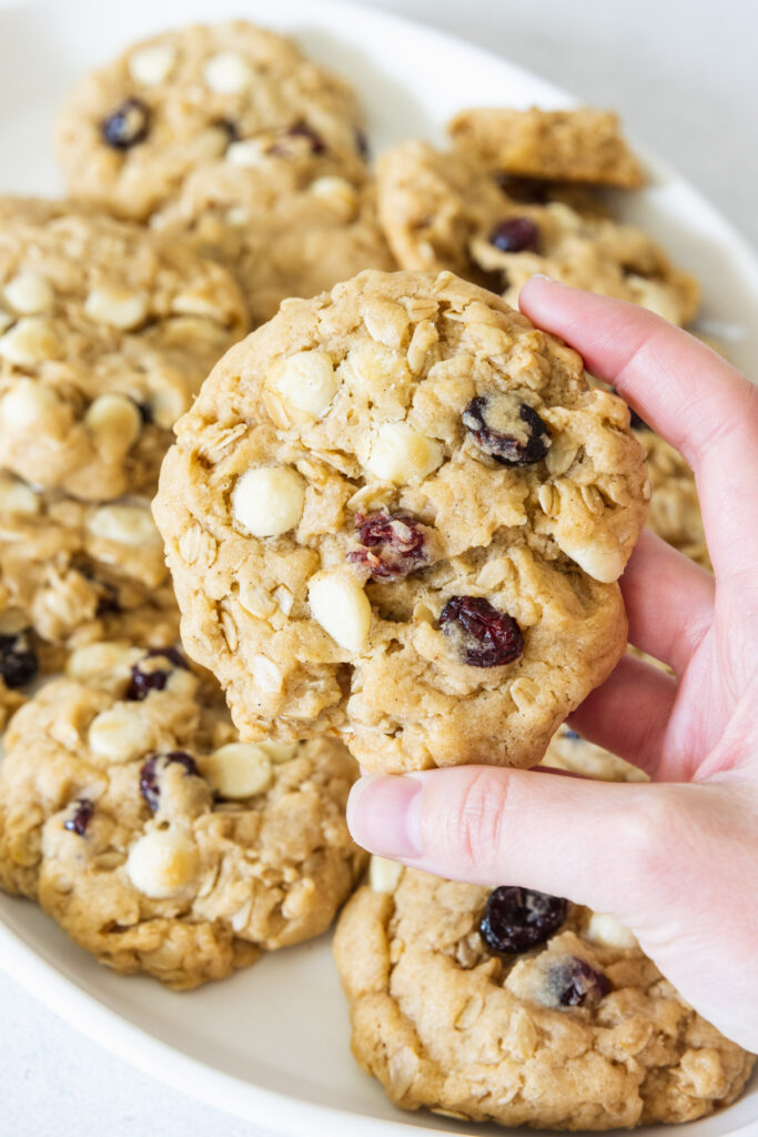 A hand holding a Cranberry White Chocolate Oatmeal Cookies