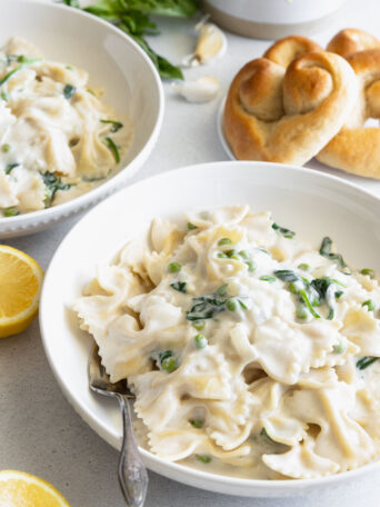 Creamy Vegan Pasta served in a white pasta bowl with fresh homemade rolls