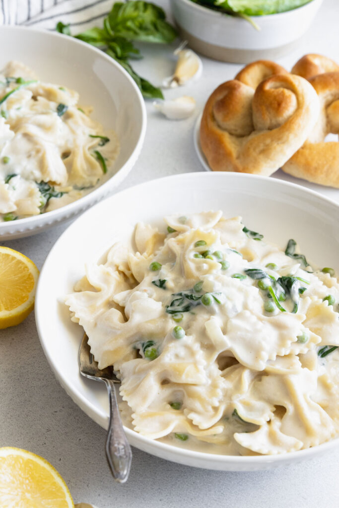 Creamy Vegan Pasta served in a white pasta bowl with fresh homemade rolls